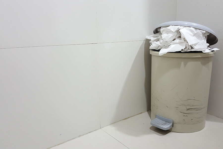 Toilet interior with toilet bin.Overflowing with used and dirty tissue paper. 
