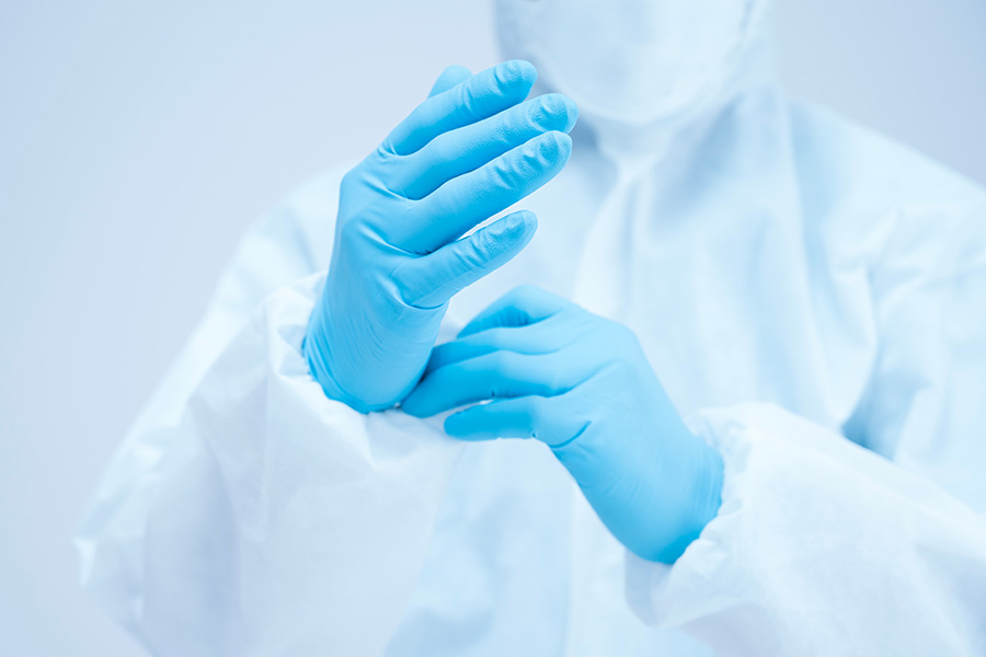 A person wearing gloves and a PPE suit