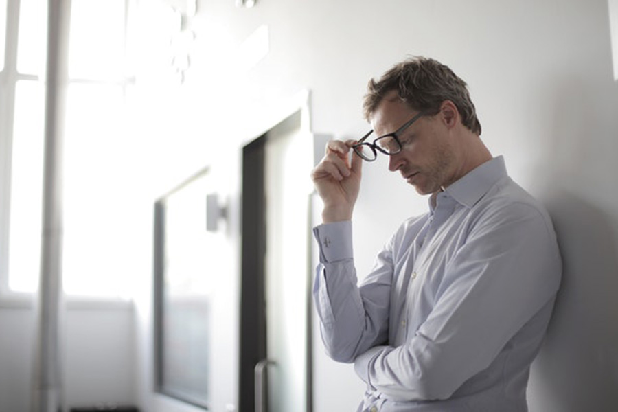 A man looking sad having received some bad news leans against a wall