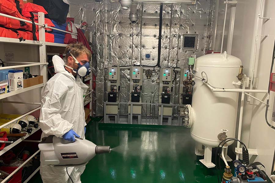 An operator wearing PPE using a fogging machine to decontaminate an area